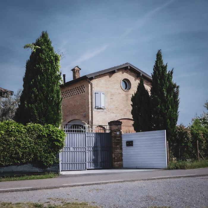 A picturesque Italian villa surrounded by lush greenery on a serene country road.
